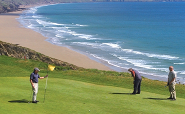 Putting on a green with the long sandy beach at Whitsand Bay beyond