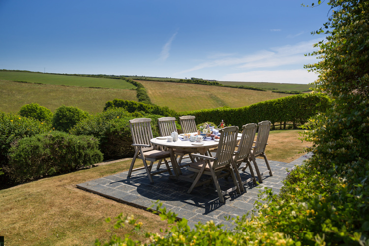 The patio with alfresco dining table has beautiful views over the garden and valley